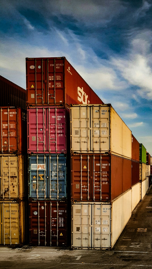 Shipping containers stacked in yard, stormy sky
